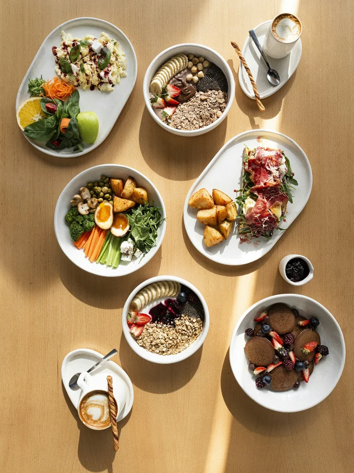 Mesa com vários pratos saudáveis: ovos, saladas, frutas e iogurte