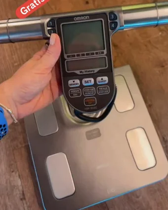 Mão segurando o visor da balança de bioimpedância